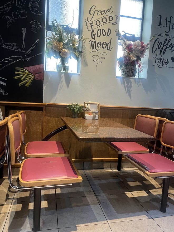 Window-side corner booth with pink seating and flower vases
